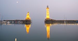 Lighthouse and statue illuminated at dusk