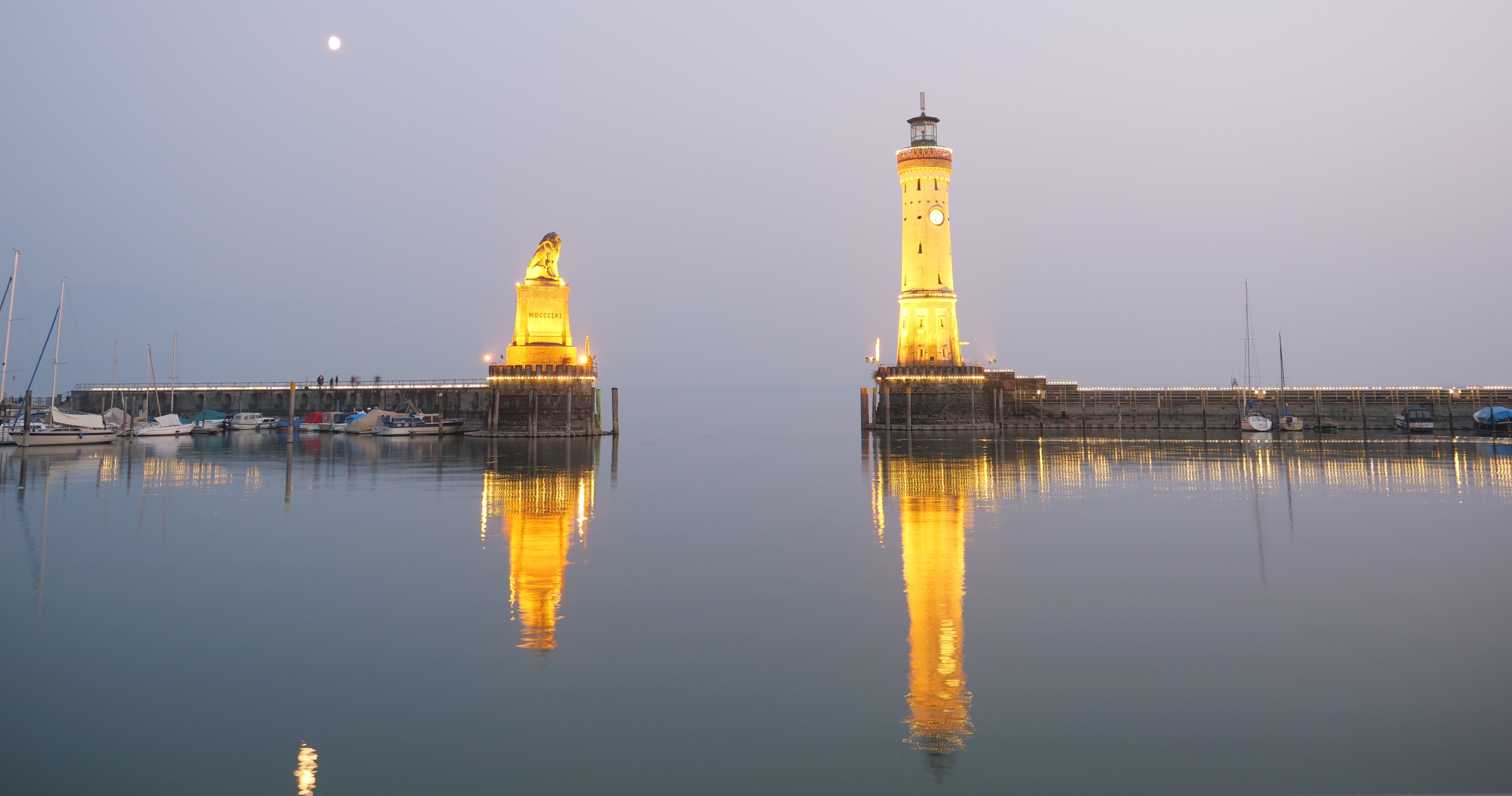 Lighthouse and statue illuminated at dusk