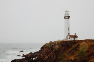 A lighthouse on a rocky ocean shore in overcast skies